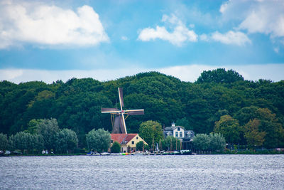 Traditional windmill by trees against sky