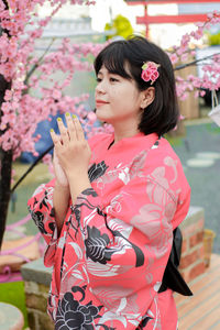 Close-up of young woman standing by flowers