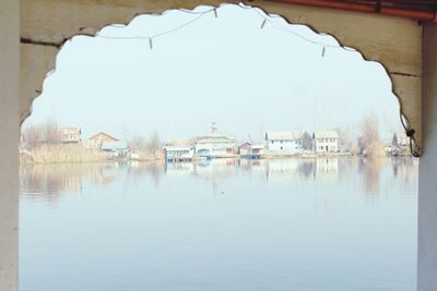 Reflection of houses in lake against clear sky