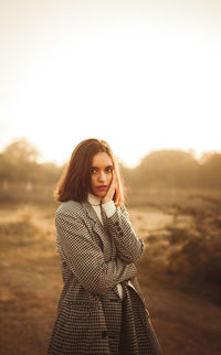 Young woman standing against sky during sunset