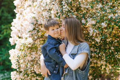 Caucasian mom kisses her three-year-old son on the cheek on a spring walk in the park person