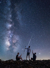 Low angle view of male friends on field against star field