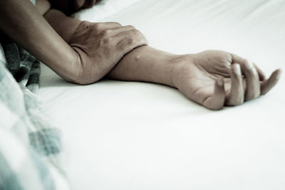 Cropped hands of man sleeping on bed