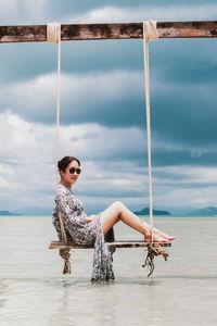 Full length portrait of young woman on beach against sky