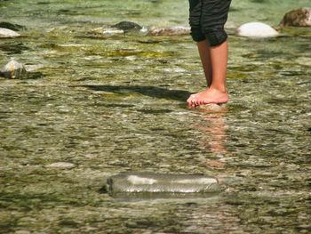 Low section of person standing in water