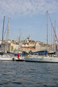 Sailboats moored at harbor against sky