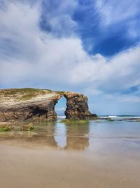 Rock formation on beach against sky