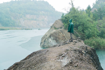 Hiker standing on rock formation at riverbank