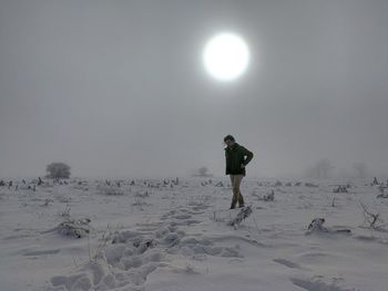 Man standing on snow covered field against sky