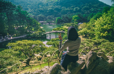 Rear view of woman on rock amidst trees