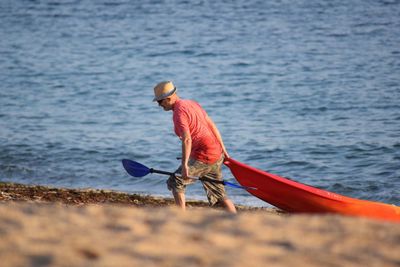 Rear view of man on beach with boat 