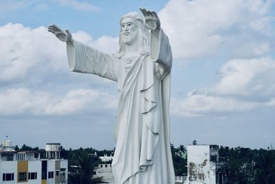 Standing majestic jesus statue blessing with both the hands against blue sky background.