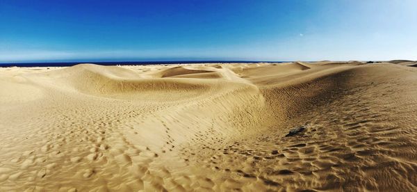 Sand dune on beach against clear sky