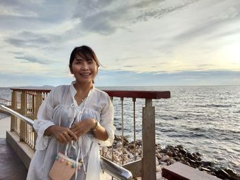 Portrait of smiling woman standing against sea