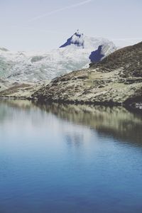 Scenic view of lake by snowcapped mountain against sky