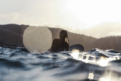 Midsection of woman by sea against sky