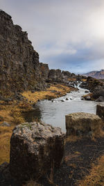 Scenic view of rocks by sea against sky