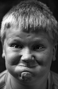 Close-up portrait of cheerful boy against black background