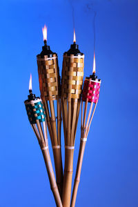 Close-up of illuminated tiki torches against blue background