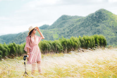 Woman with umbrella on field against sky