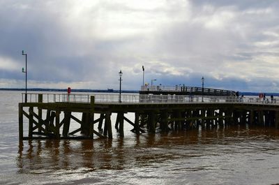 Pier on sea against cloudy sky