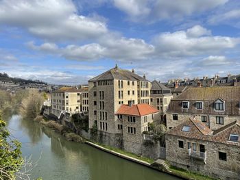 Buildings by river against sky in city