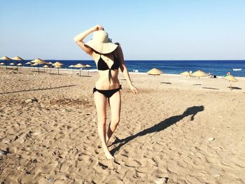 Woman standing on beach against sky