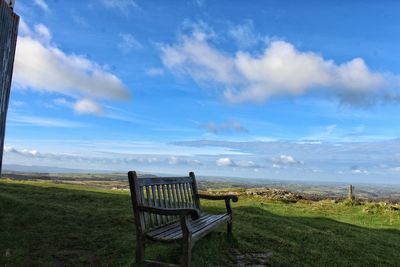Empty chairs on field against sky