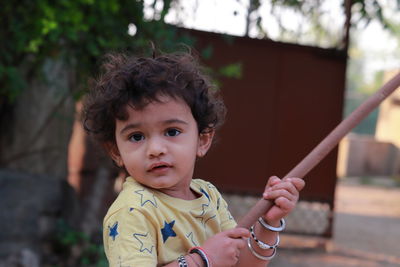 An indian little child looking at the camera holding a wooden stick