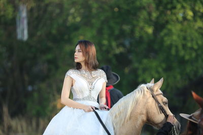 Low angle view of young woman riding horse in forest