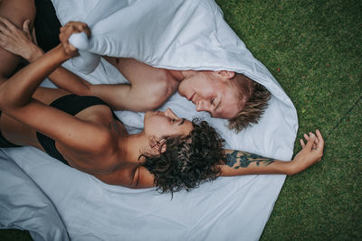 Directly above shot of couple lying on towel over grass