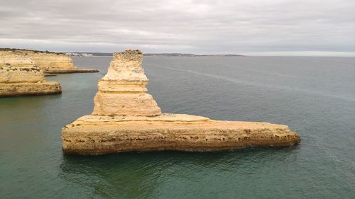 Rock formation in sea against sky