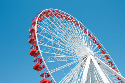 Low angle view of ferris wheel against clear blue sky