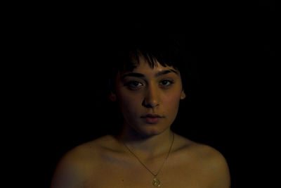Portrait of young woman against black background