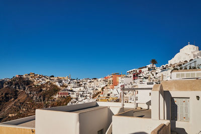 Buildings in city against clear blue sky