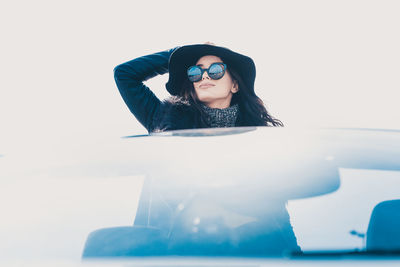 Young woman wearing sunglasses against white background