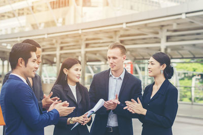 Business colleagues discussing while standing on footpath in city