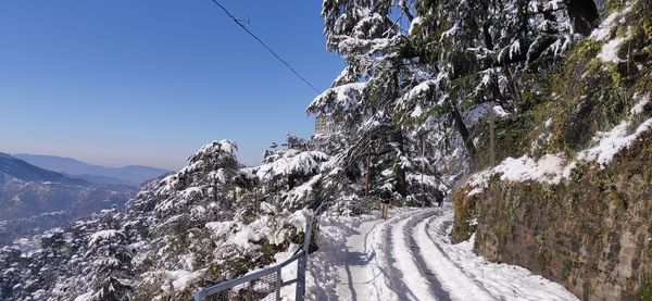 Snow covered road by mountain against sky