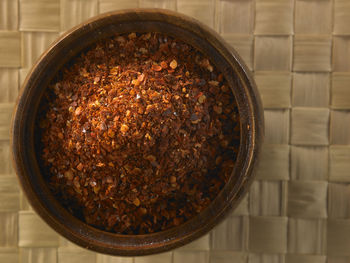 Directly above shot of chili flakes in wooden bowl on table
