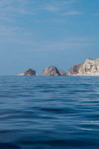 Rock formations in sea against blue sky