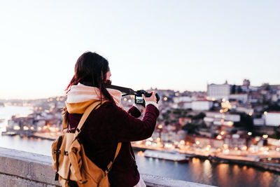 Woman in porto bridge taking pictures with camera at sunset. tourism in city europe. travel