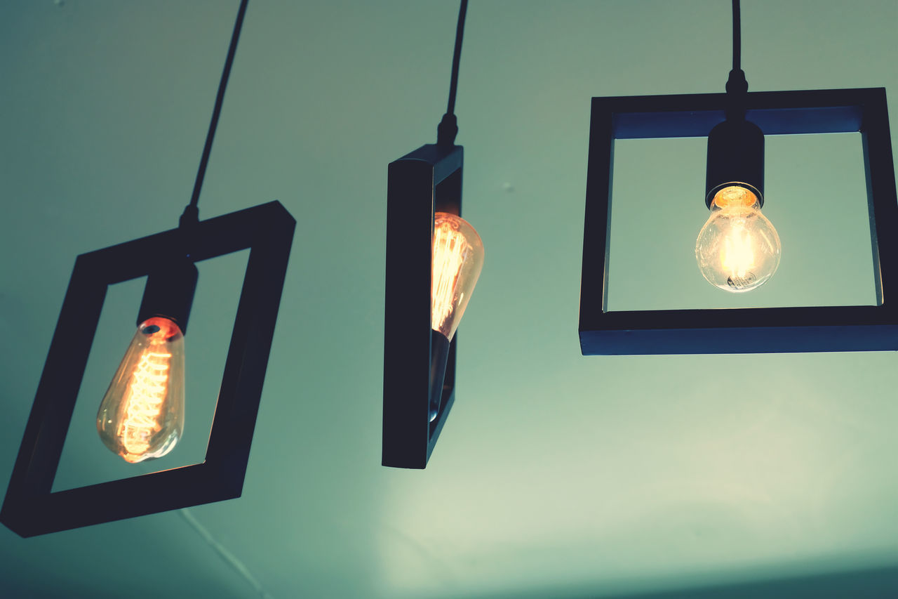 LOW ANGLE VIEW OF LIGHT BULB HANGING AGAINST WALL