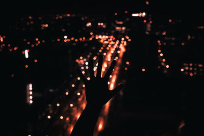 Close-up of hands against illuminated lights