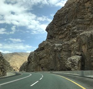 Road leading towards rock formation against sky