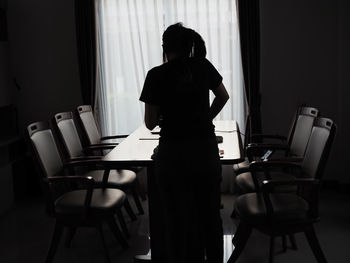 Rear view of woman sitting on table at home