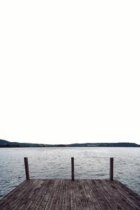 Wooden pier over sea against clear sky