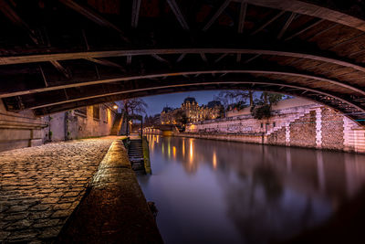 Arch bridge over river at night in paris