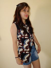 Portrait of young woman standing against wall