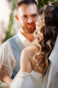 Bridegroom embracing while standing outdoors