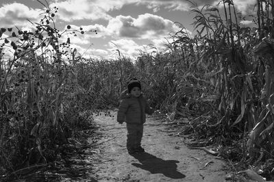 Boy standing on footpath amidst farm